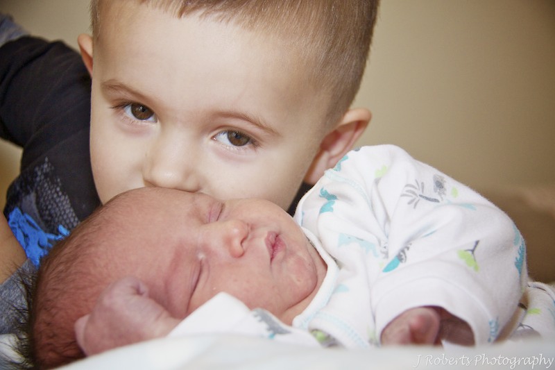 Big brother giving newborn baby a kiss - newborn baby portrait photography sydney